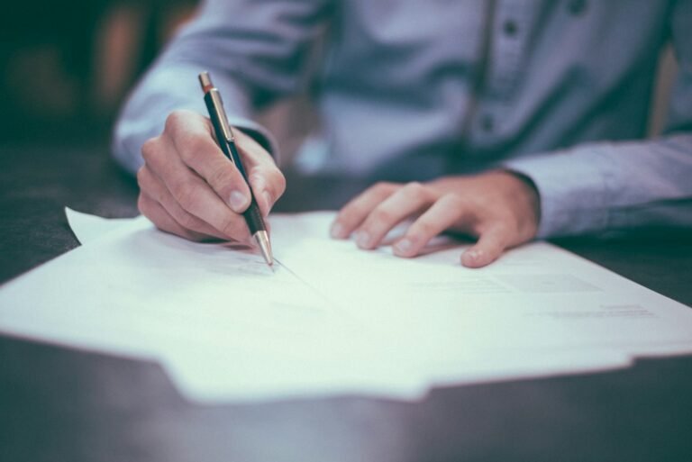 Mains de personnes examinant et signant des documents sur une table de travail