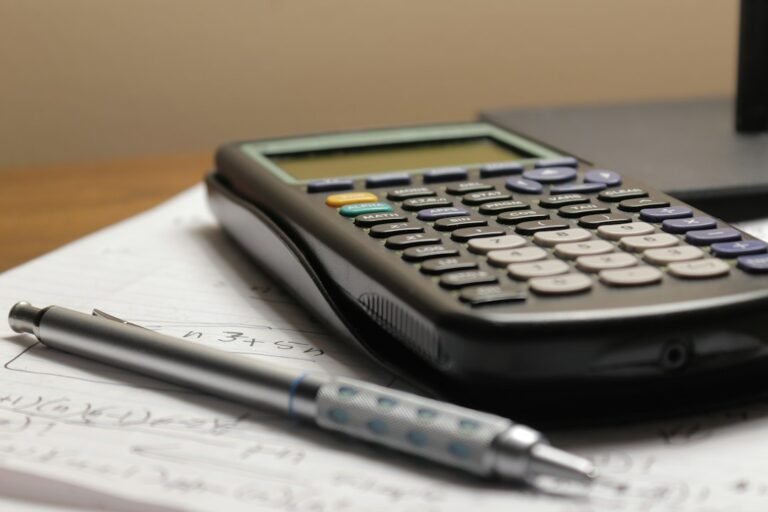 Calculatrice et stylo posés sur une feuille pour vérifier les montants d’une fiche de paie