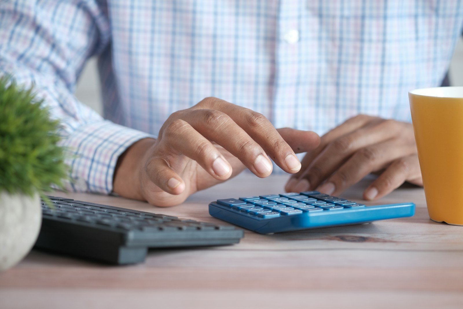 Main utilisant une calculatrice à côté de documents financiers